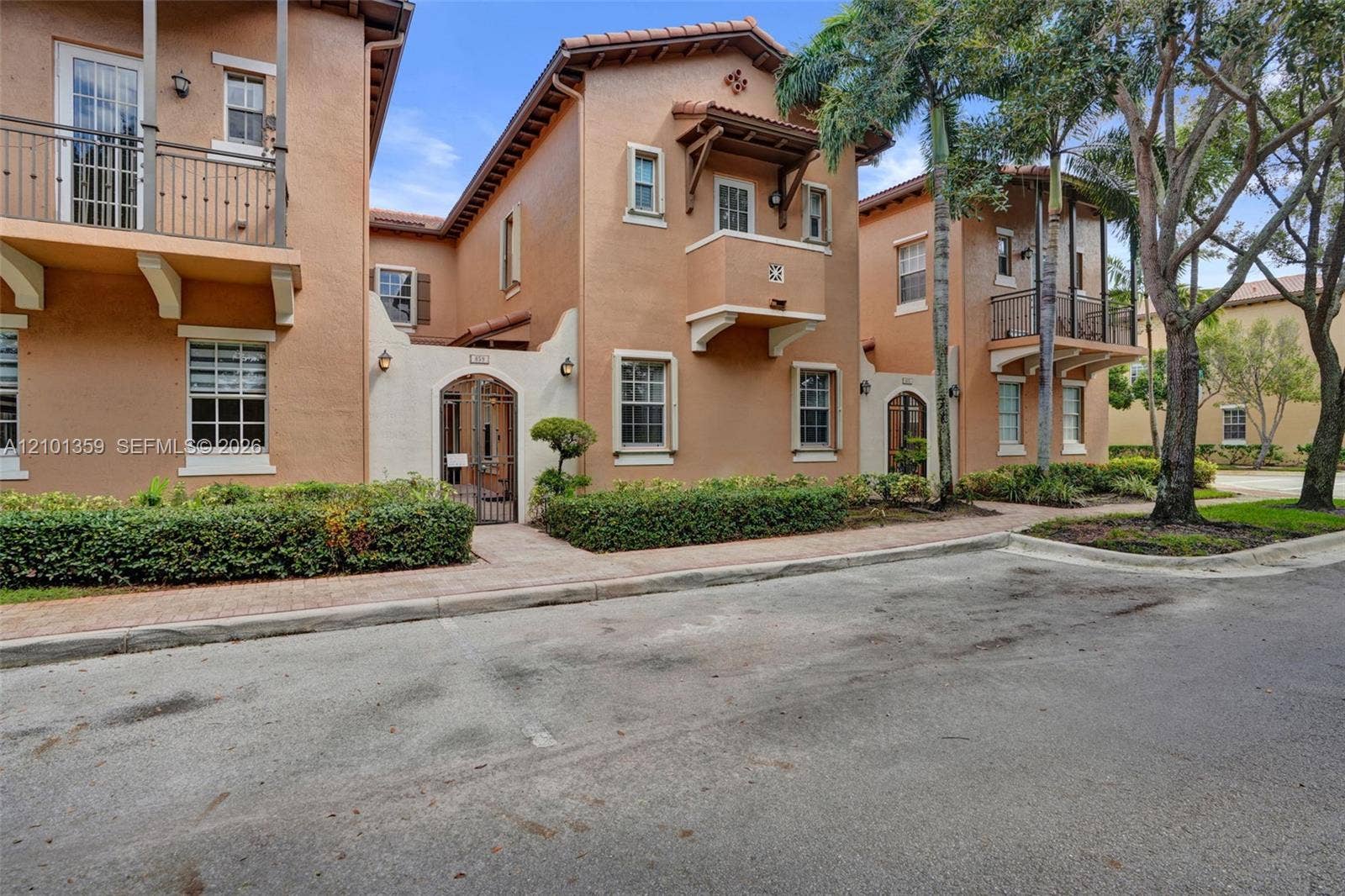 859 SW 147th Terrace, #0, Pembroke Pines, FL 33027 Mediterranean-style stucco exterior featuring terracotta roof tiles, wrought-iron balcony railings, arched gated entryways, and upper-level decorative corbels