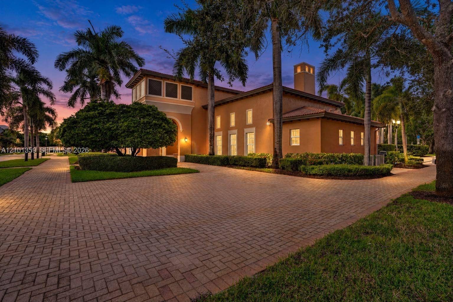 859 SW 147th Terrace, #0, Pembroke Pines, FL 33027 Stucco exterior featuring a paver driveway, multiple vertical windows, a prominent chimney, and mature palm trees