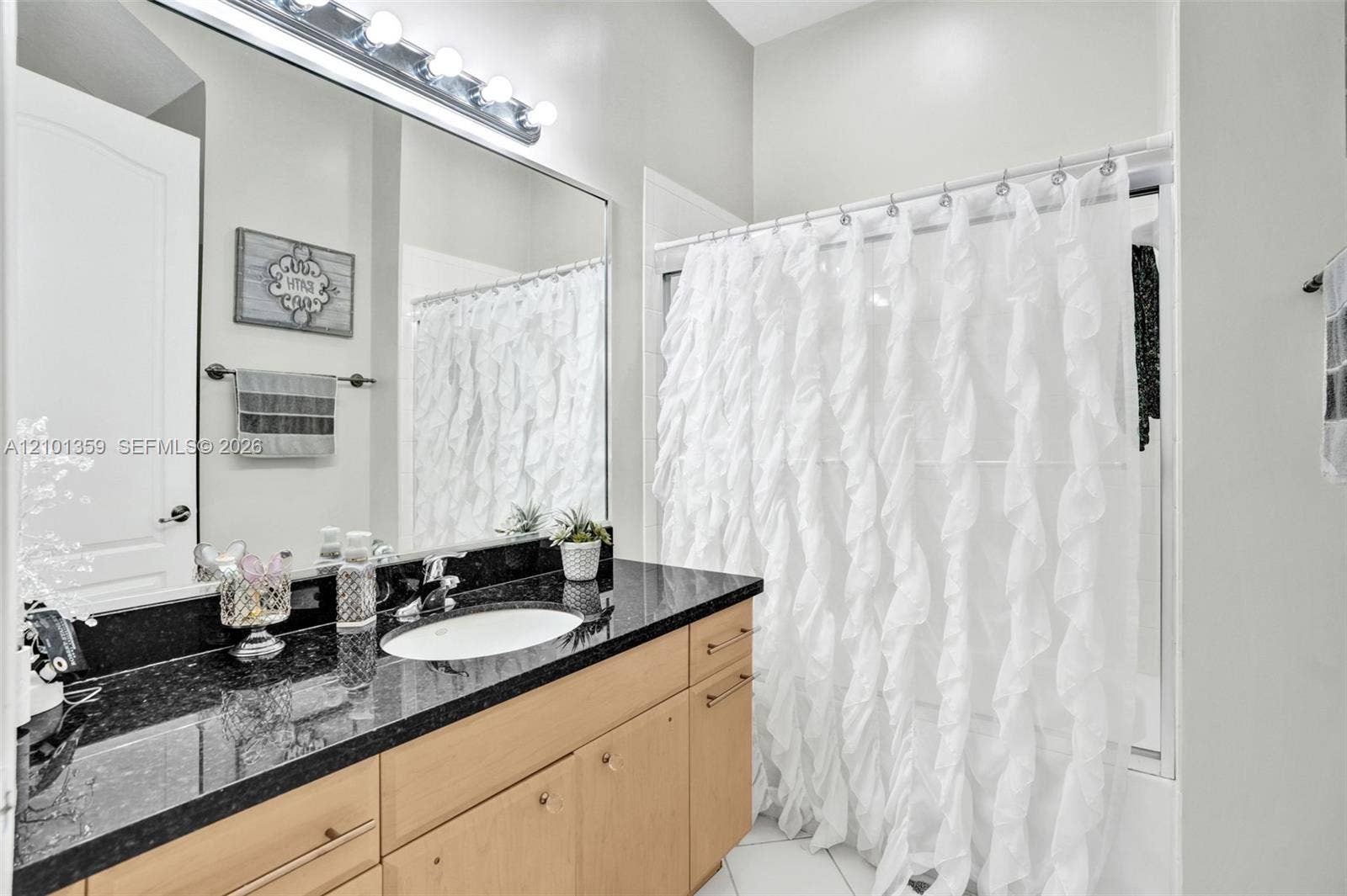 859 SW 147th Terrace, #0, Pembroke Pines, FL 33027 Full-width vanity with dark stone countertop, integrated oval basin, light-finish cabinetry, oversized wall-to-wall mirror, and multi-bulb vanity lighting