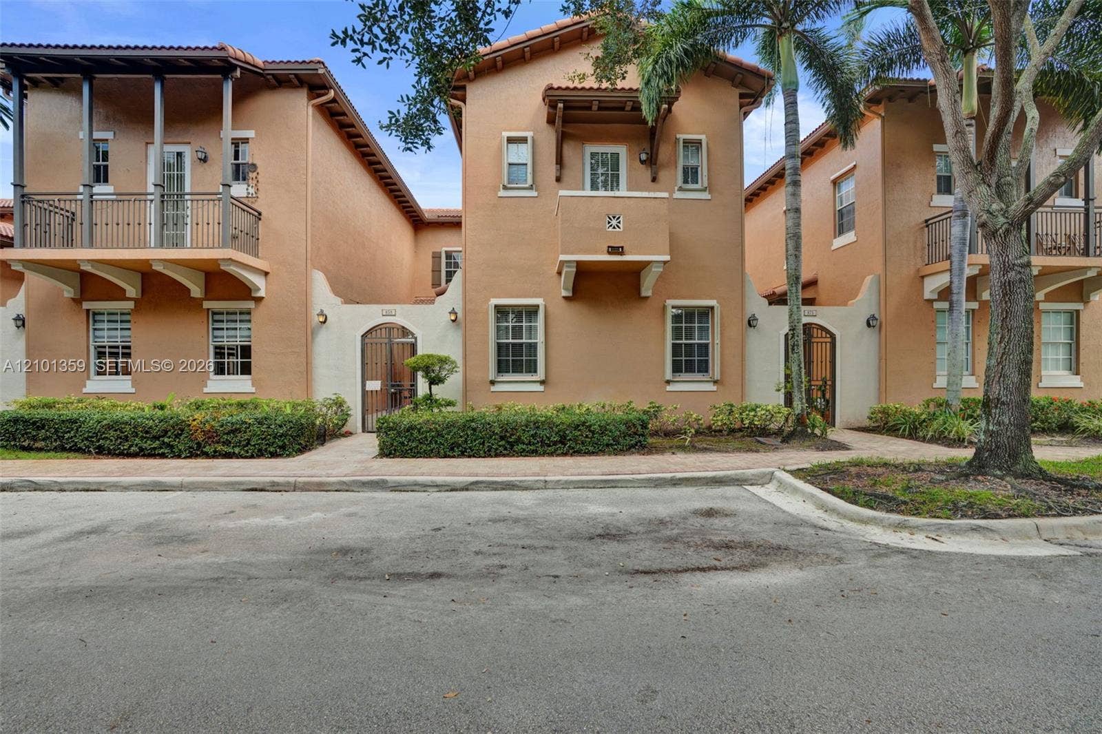 859 SW 147th Terrace, #0, Pembroke Pines, FL 33027 Mediterranean-style multi-level exterior featuring a stucco facade, decorative corbels, wrought-iron balcony railings, and arched courtyard gates