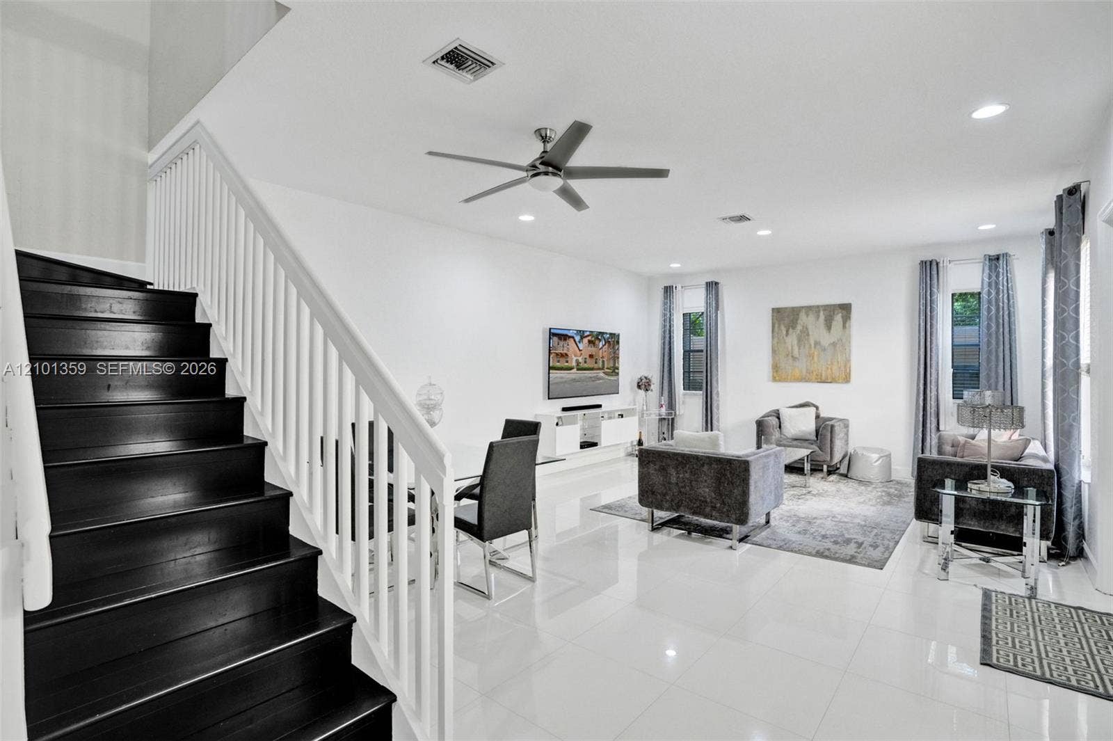 859 SW 147th Terrace, #0, Pembroke Pines, FL 33027 Open-concept interior featuring large-format tile flooring, a staircase with dark-finished treads and white handrails, recessed ceiling lighting, and a modern ceiling fan