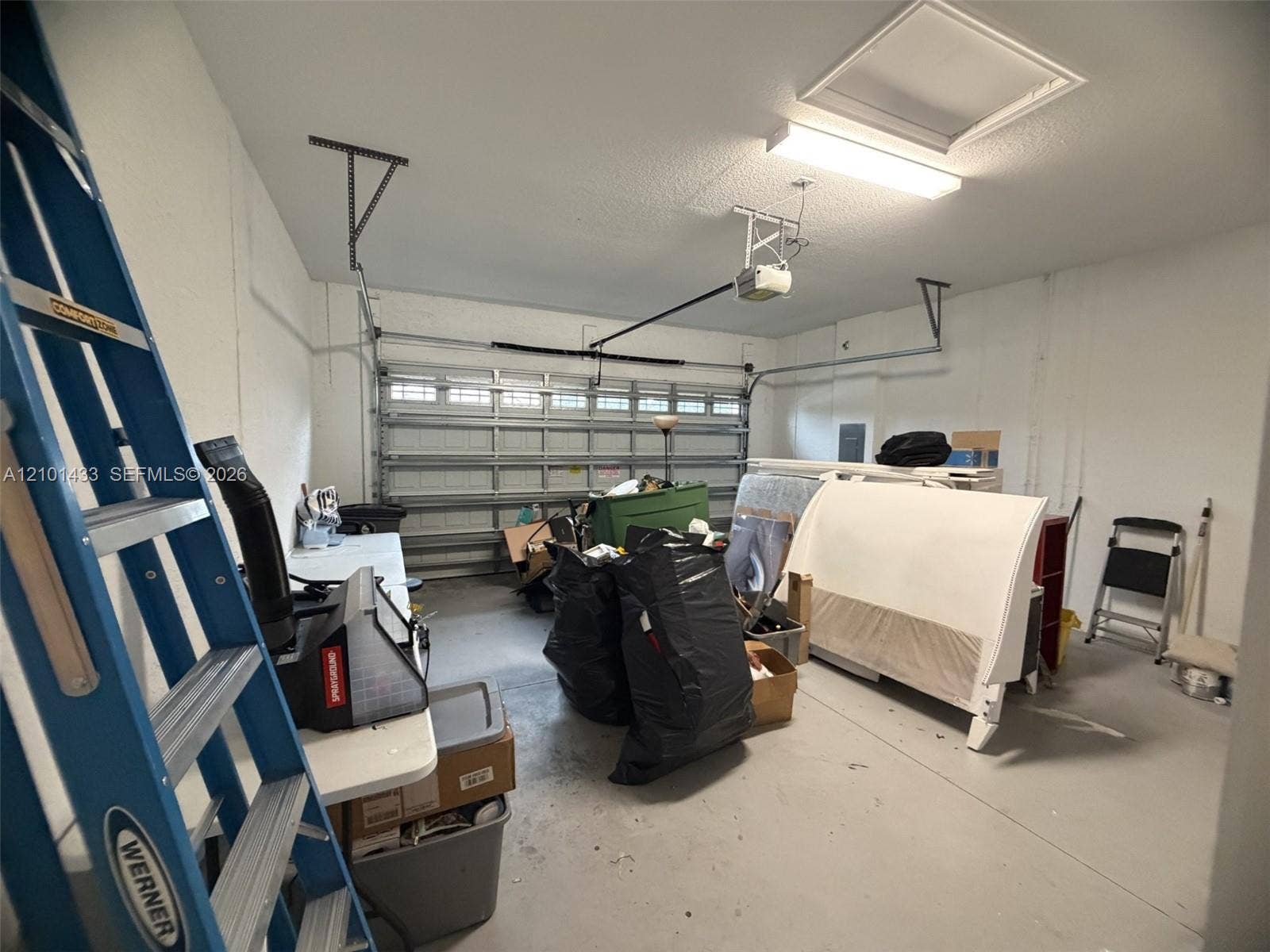 Attached garage featuring a white overhead door and painted concrete flooring