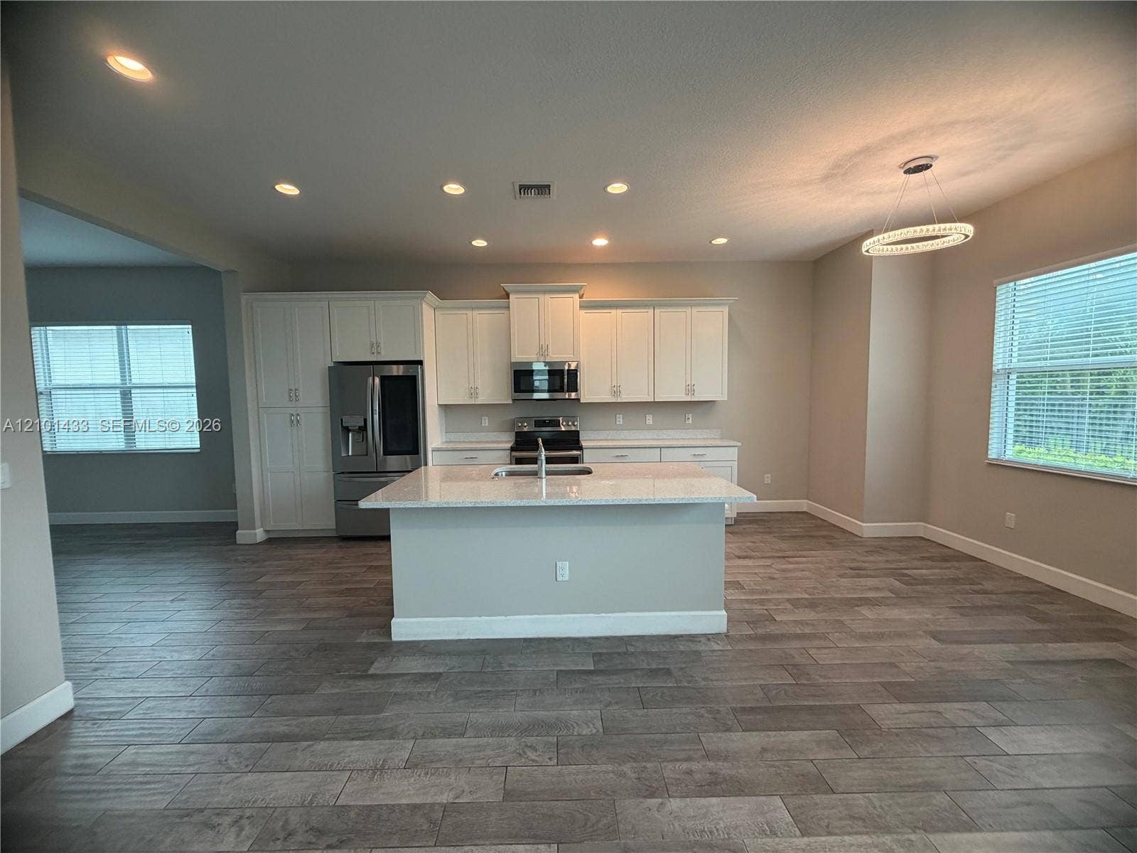 Kitchen featuring a central island with countertop, white cabinetry, stainless steel appliances, and recessed lighting