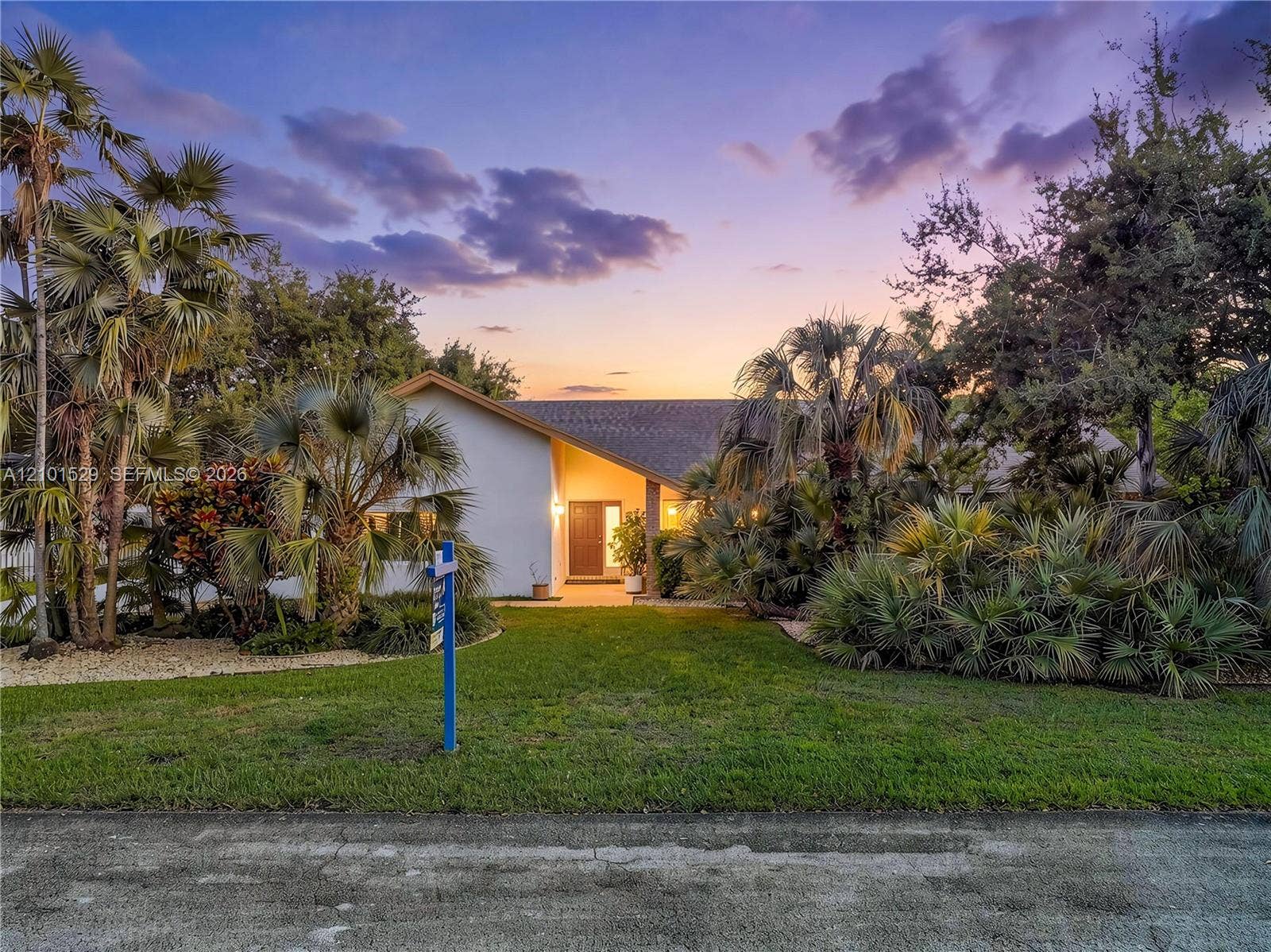 16761 SW 278th Street, Homestead, FL 33031 Pitched roofline, white exterior, mature palm trees, diverse landscaping, and a manicured lawn