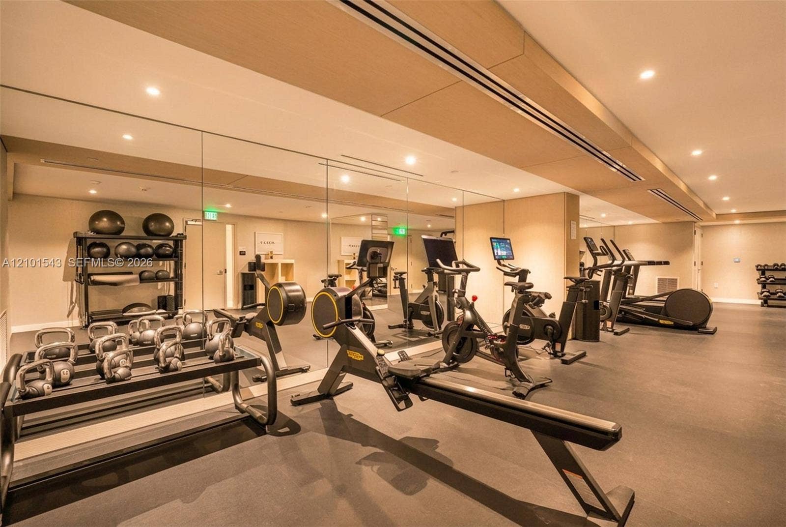 Fitness space featuring rubberized flooring, expansive floor-to-ceiling mirrored walls, recessed lighting, and wood-finish ceiling accents