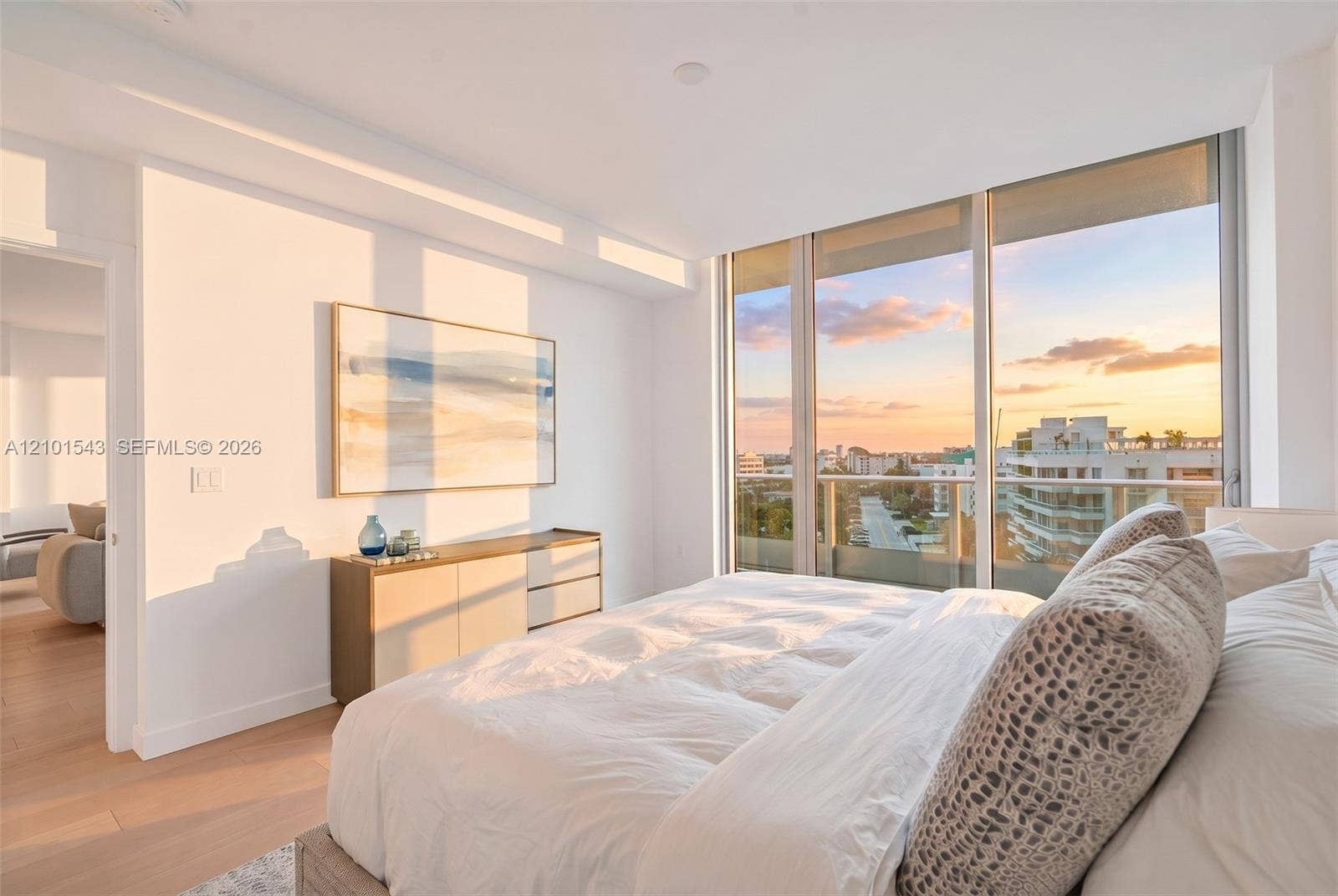 Floor-to-ceiling windows, private balcony, wood-finish flooring, and neutral wall tones