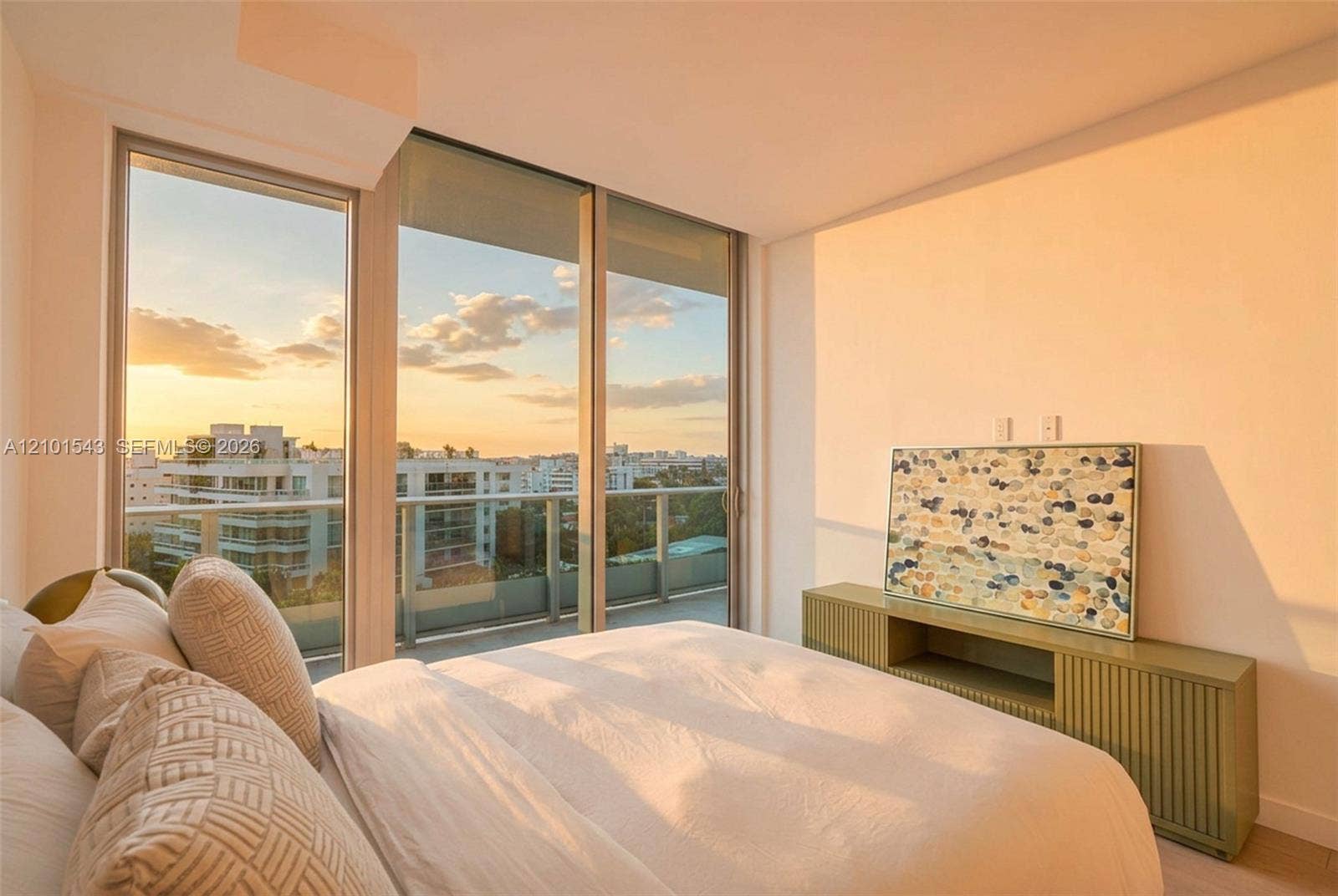 Floor-to-ceiling windows, sliding glass door, private balcony with metal railing, and neutral wall finishes