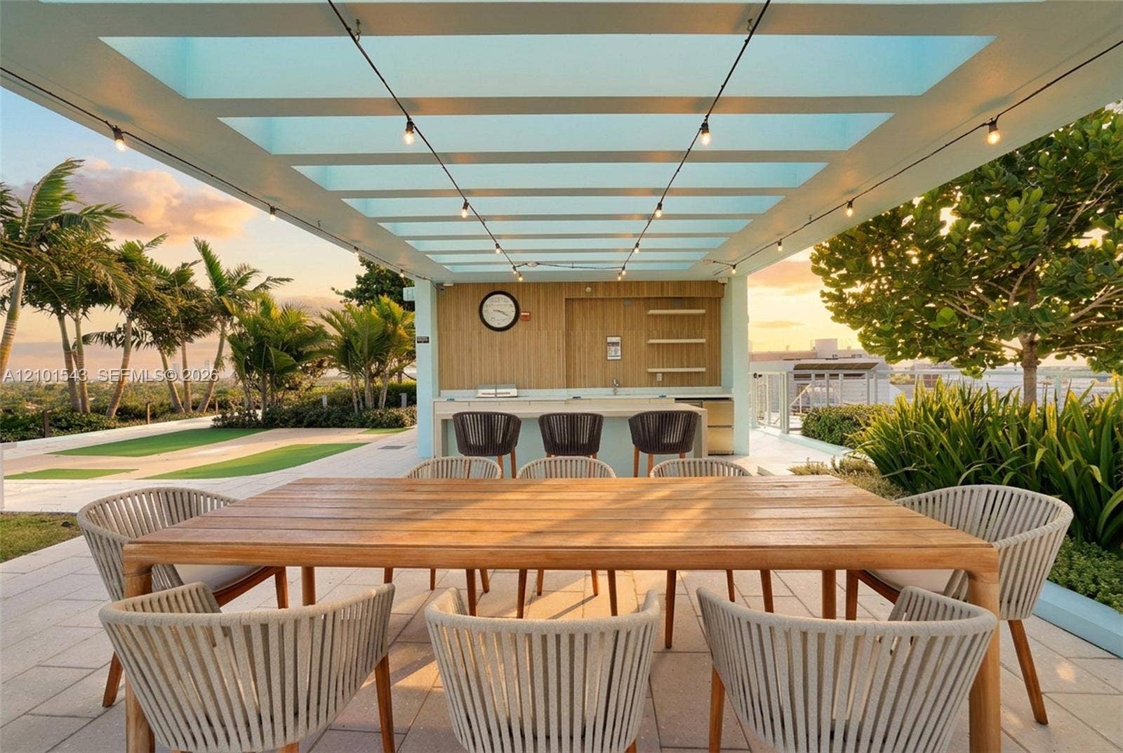 Covered outdoor terrace featuring a wood-paneled wet bar, stone-finished countertop, pergola structure, and light-tone tile flooring