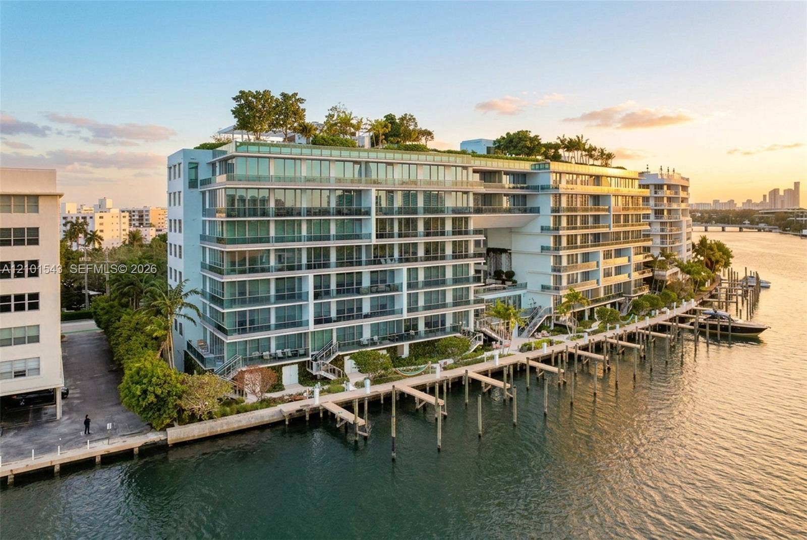 Waterfront residential complex featuring multiple levels of glass-railed balconies, a rooftop terrace, private deep-water dockage, and expansive floor-to-ceiling windows