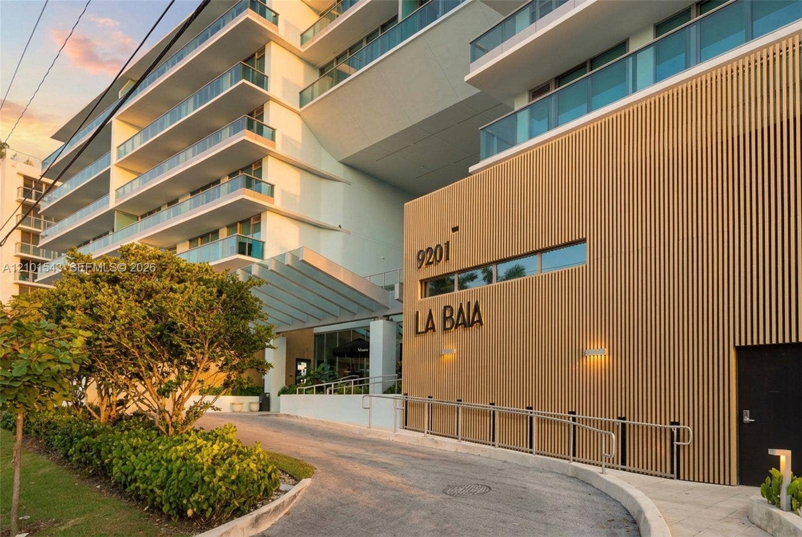 Contemporary architectural exterior featuring vertical wood-slat cladding, multi-level balconies with glass railings, and a covered porte-cochre entry
