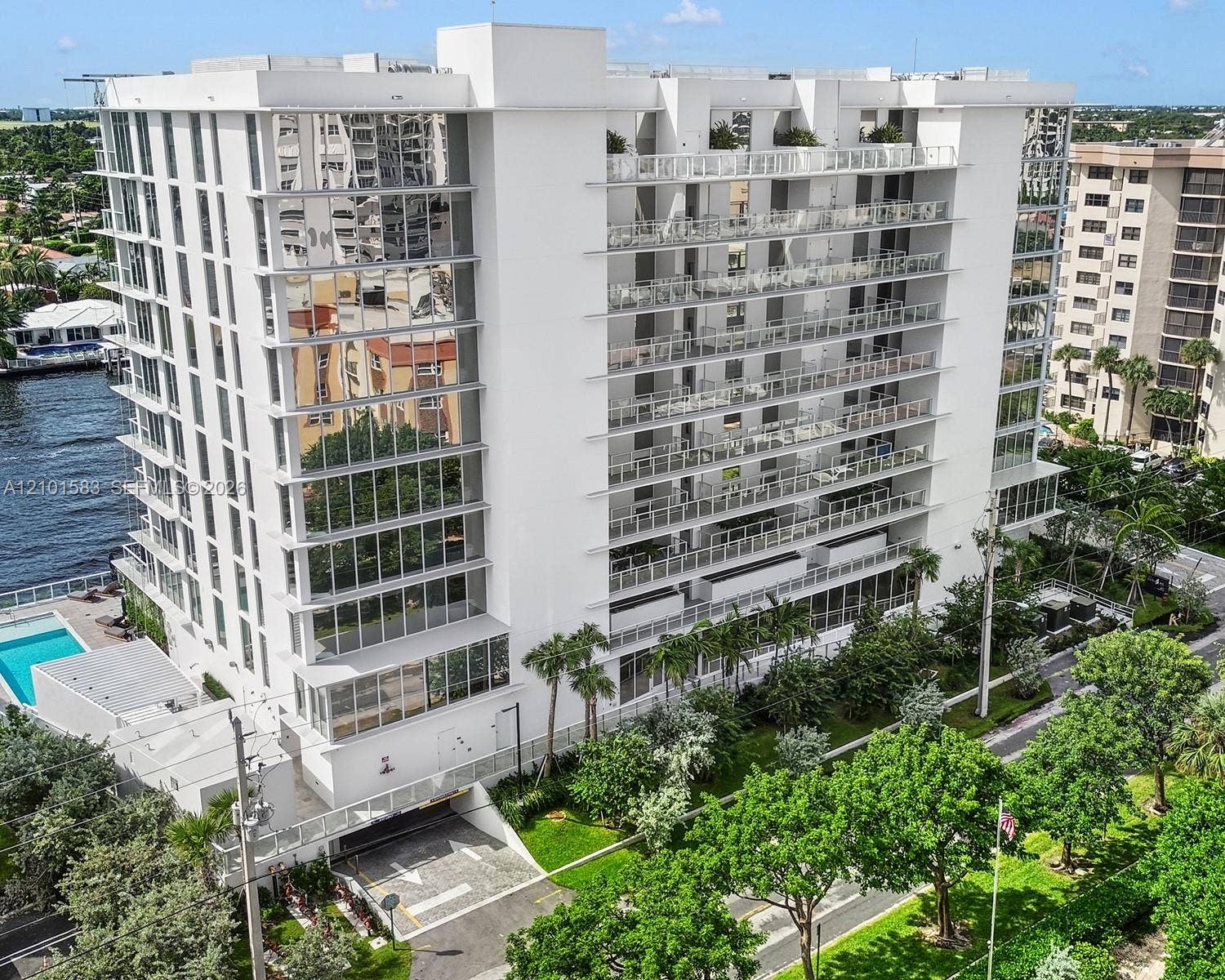407 N Riverside Drive, #604, Pompano Beach, Pompano Beach, FL 33062 Multi-story residential building featuring floor-to-ceiling glass paneling, tiered cantilevered balconies with glass railings, an attached swimming pool, and dedicated subterranean parking access
