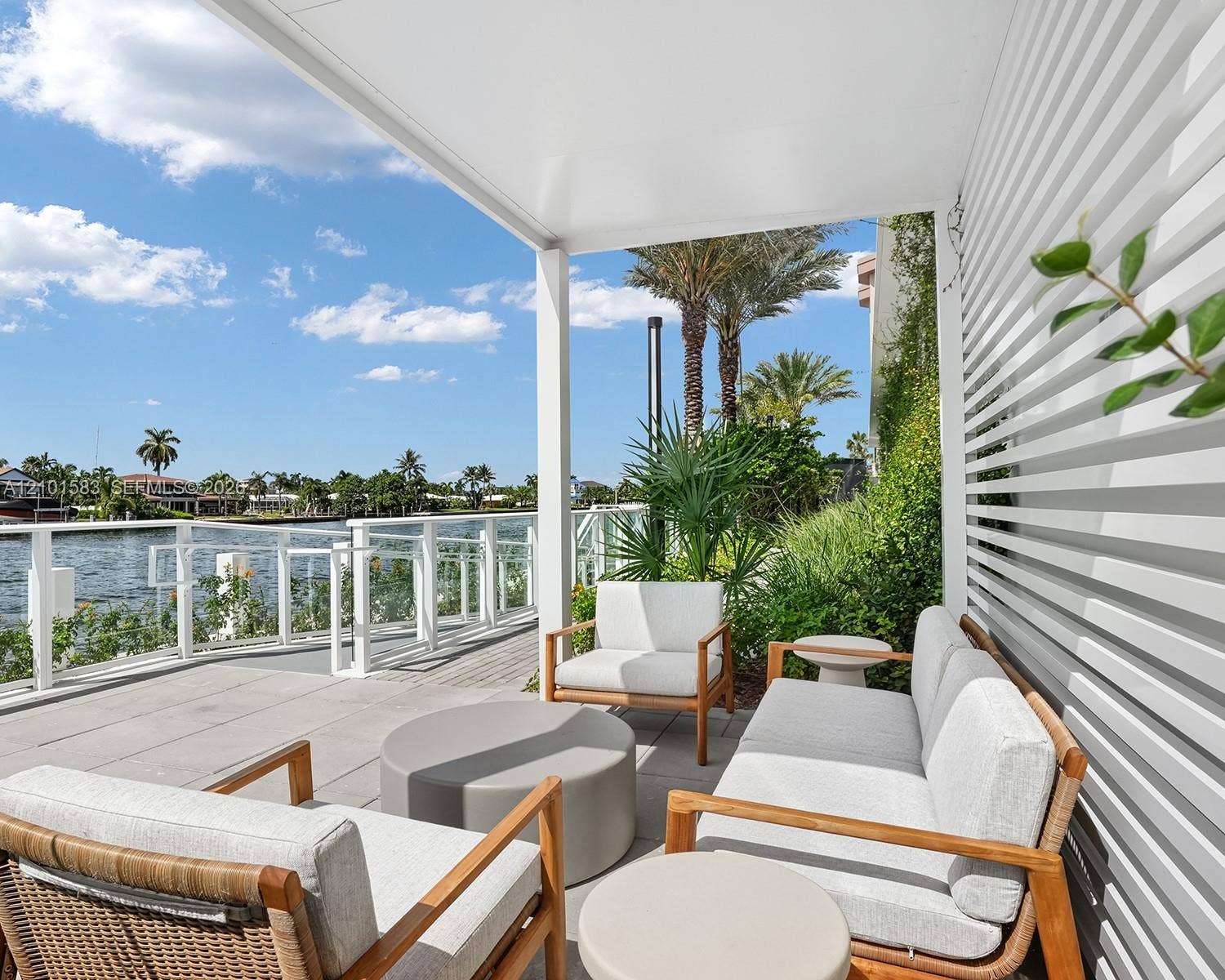 407 N Riverside Drive, #604, Pompano Beach, Pompano Beach, FL 33062 Covered patio featuring concrete tile flooring, horizontal slat privacy screen, and a glass-paneled railing overlooking the water