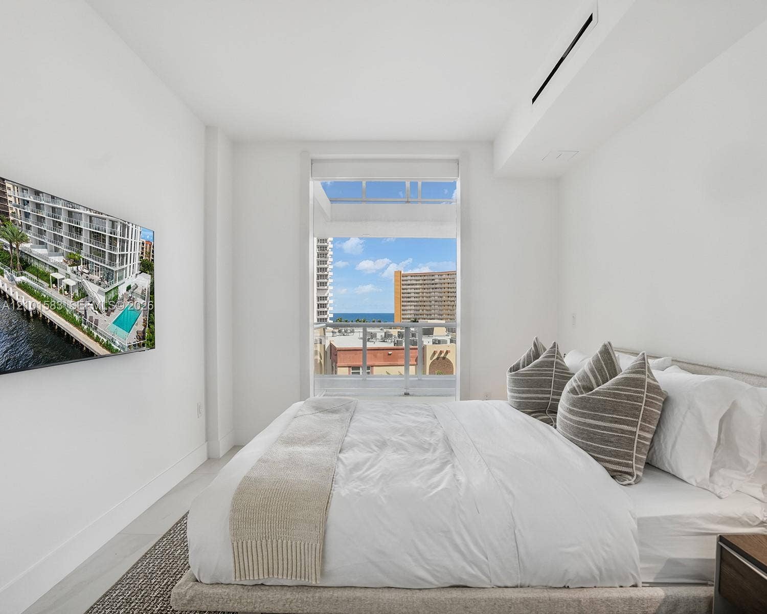 407 N Riverside Drive, #604, Pompano Beach, Pompano Beach, FL 33062 Floor-to-ceiling window featuring a glass balcony railing, neutral tile flooring, wall-mounted ductless climate control, and prominent water and cityscape scenery