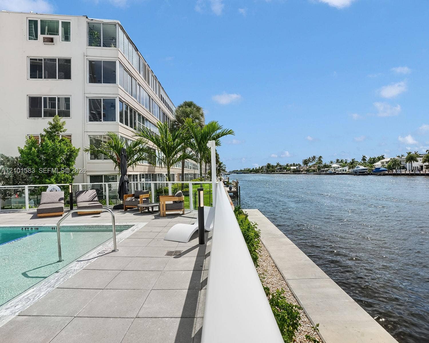 407 N Riverside Drive, #604, Pompano Beach, Pompano Beach, FL 33062 Waterfront pool area featuring expansive stone tile decking, a glass panel railing system, and manicured landscaping