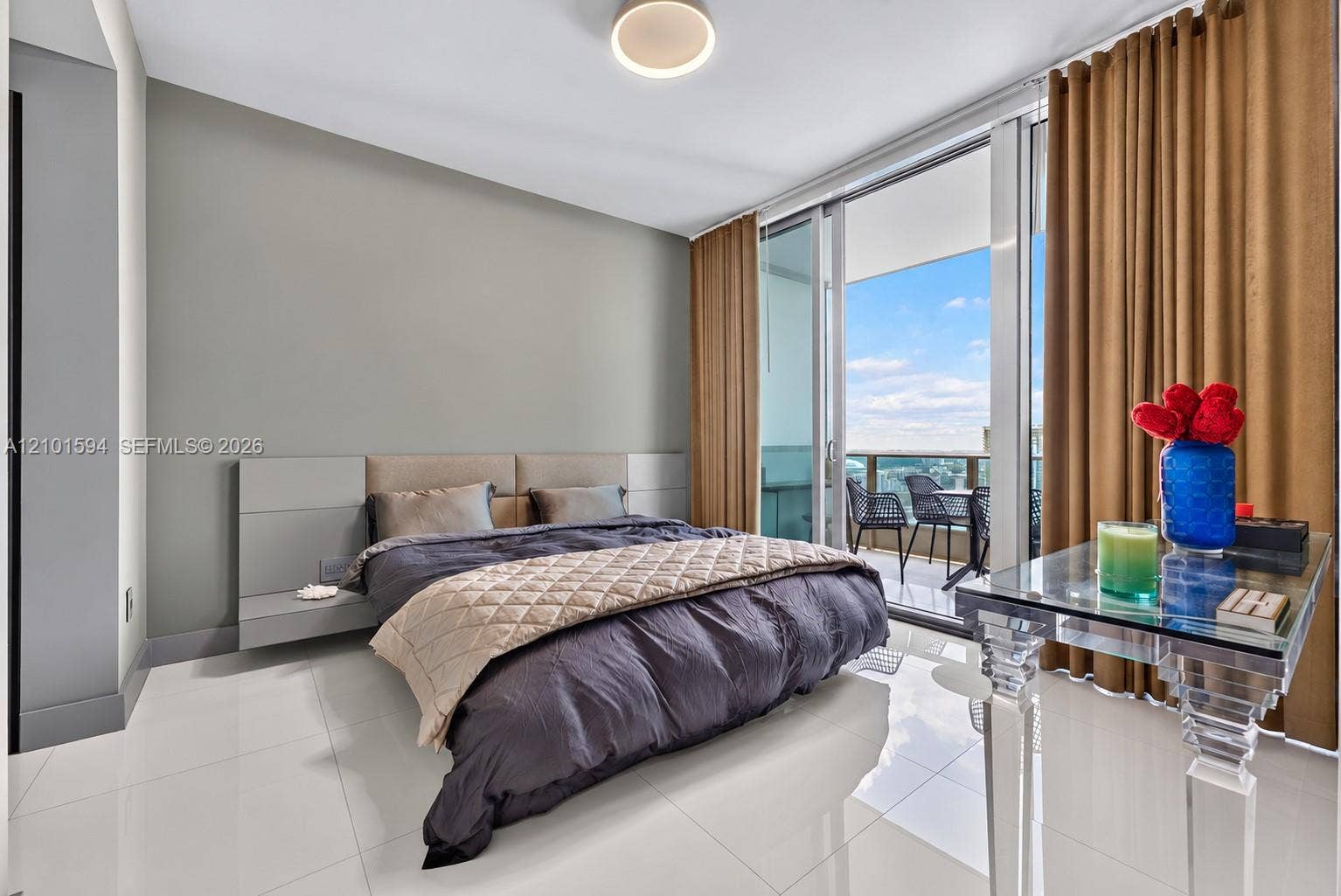 Primary bedroom with floor-to-ceiling glass, balcony access and skyline views.