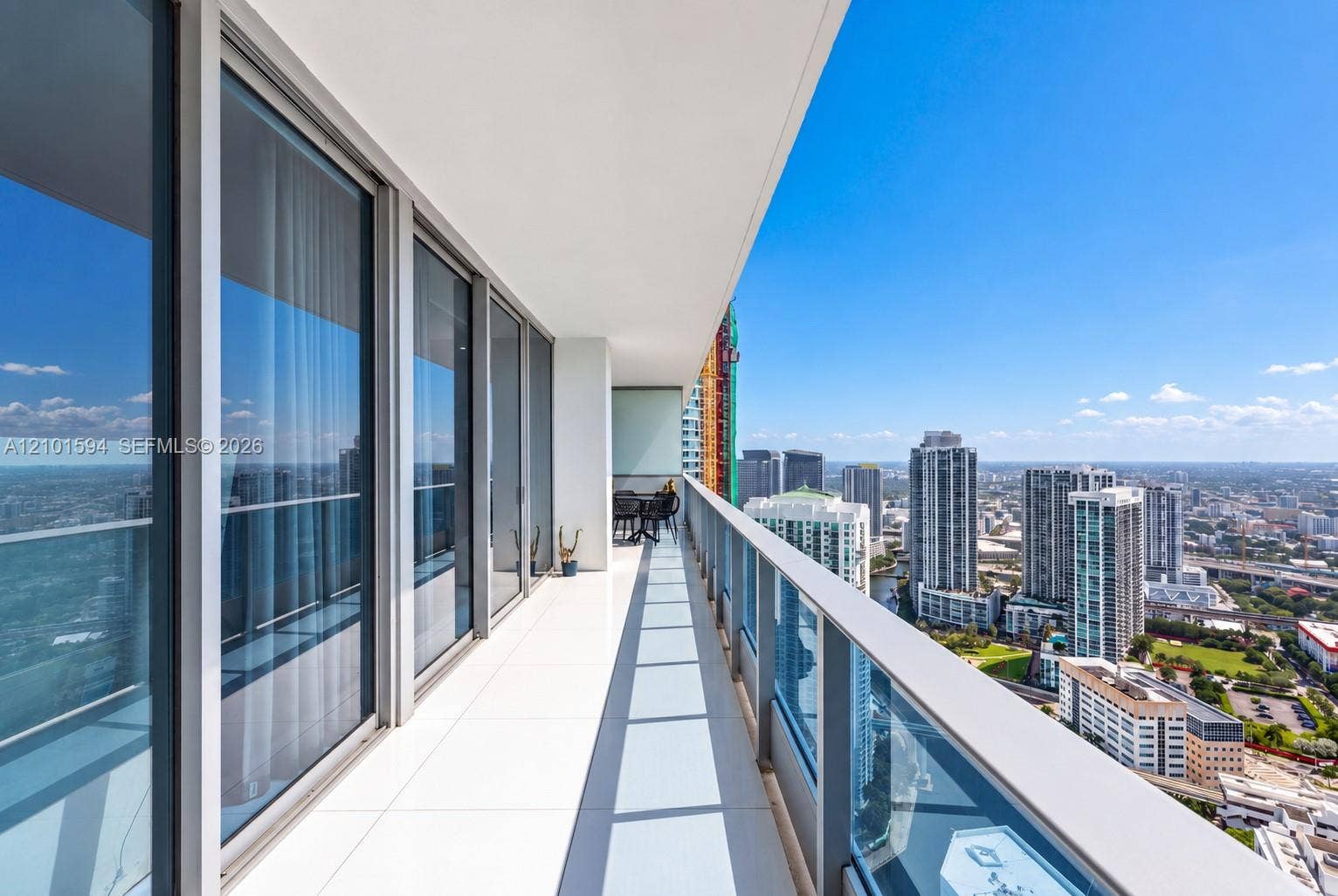 Long private balcony with glass railing and expansive skyline views.