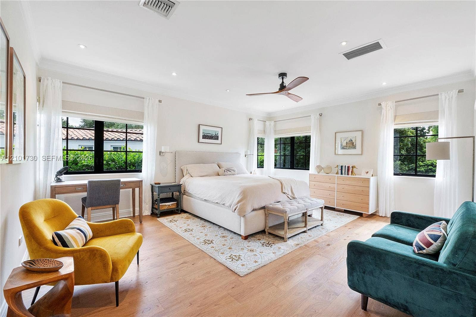 435 W 51st Street, Miami Beach, FL 33140 Neutral-toned bedroom featuring wood-finish flooring, multi-pane black-trimmed windows, and a ceiling fan with integrated lighting