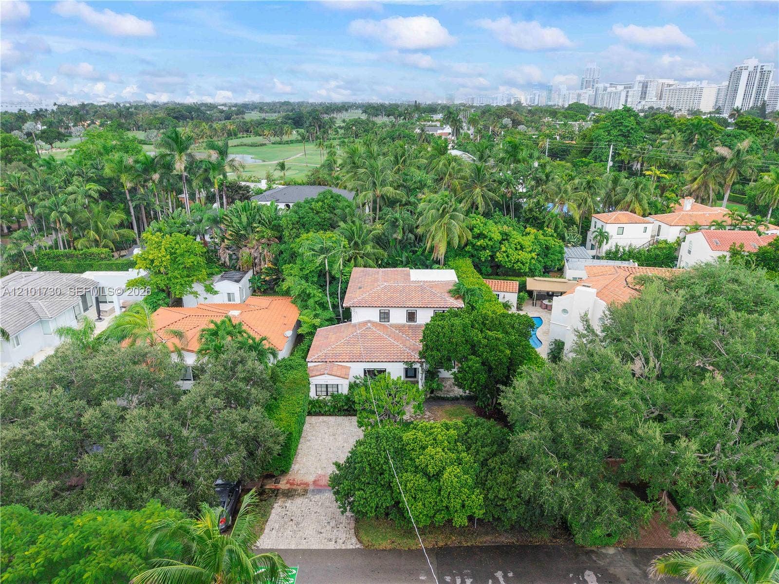 435 W 51st Street, Miami Beach, FL 33140 Multi-level residence featuring a clay tile roof, light-toned exterior finish, paver driveway, and mature landscaping