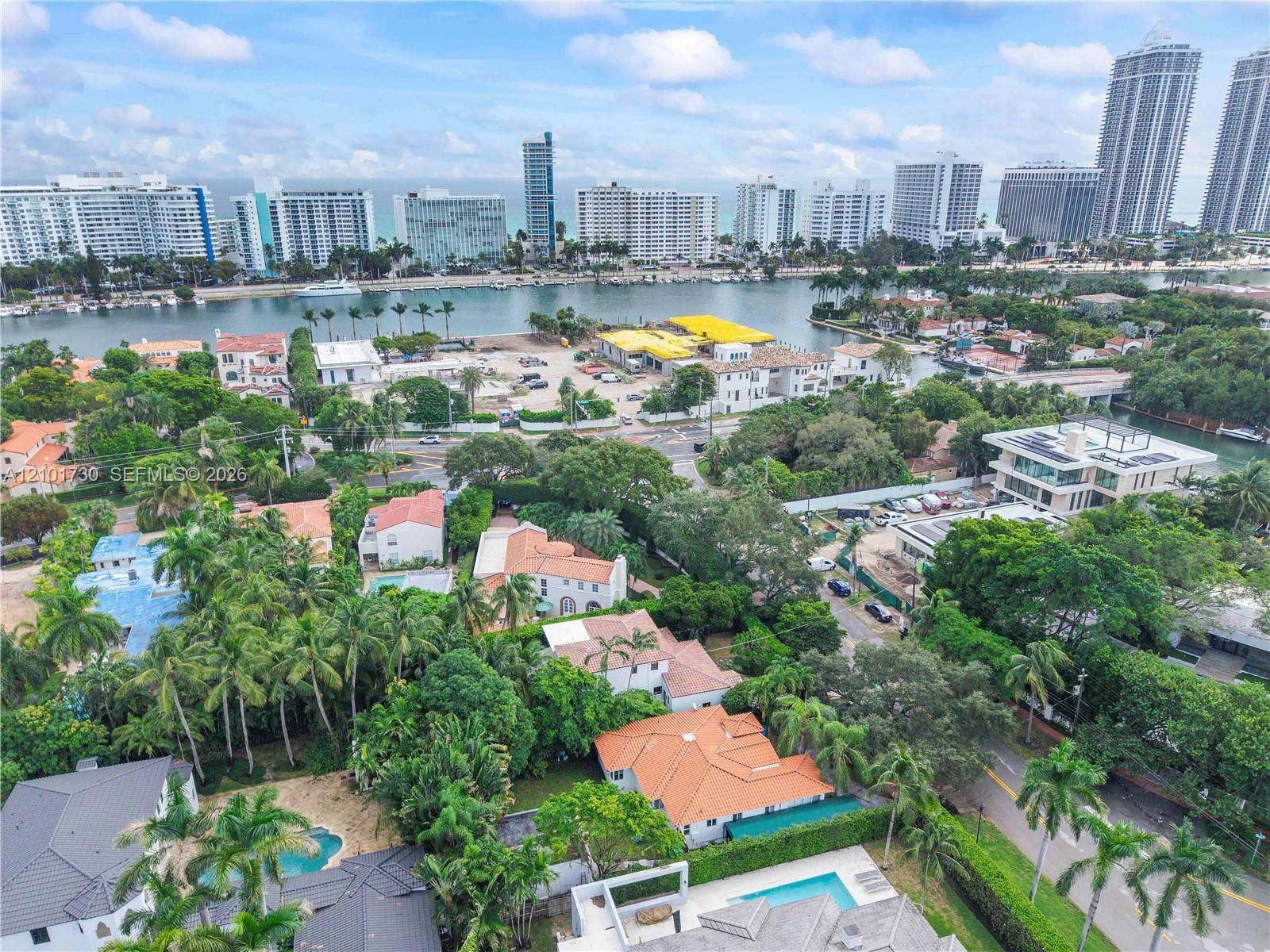 435 W 51st Street, Miami Beach, FL 33140 Aerial perspective of a coastal residential area featuring tile roofing, mature tropical foliage, private swimming pools, and proximity to the waterfront