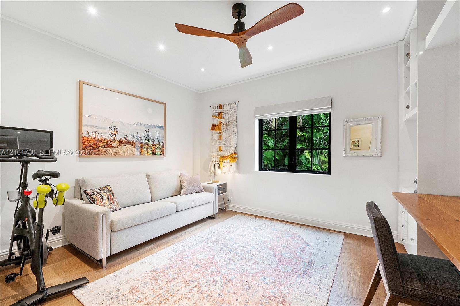 435 W 51st Street, Miami Beach, FL 33140 Room featuring wood-finish flooring, a modern three-blade ceiling fan, recessed lighting, a multi-pane black-framed window, and built-in shelving with an attached wooden desk surface
