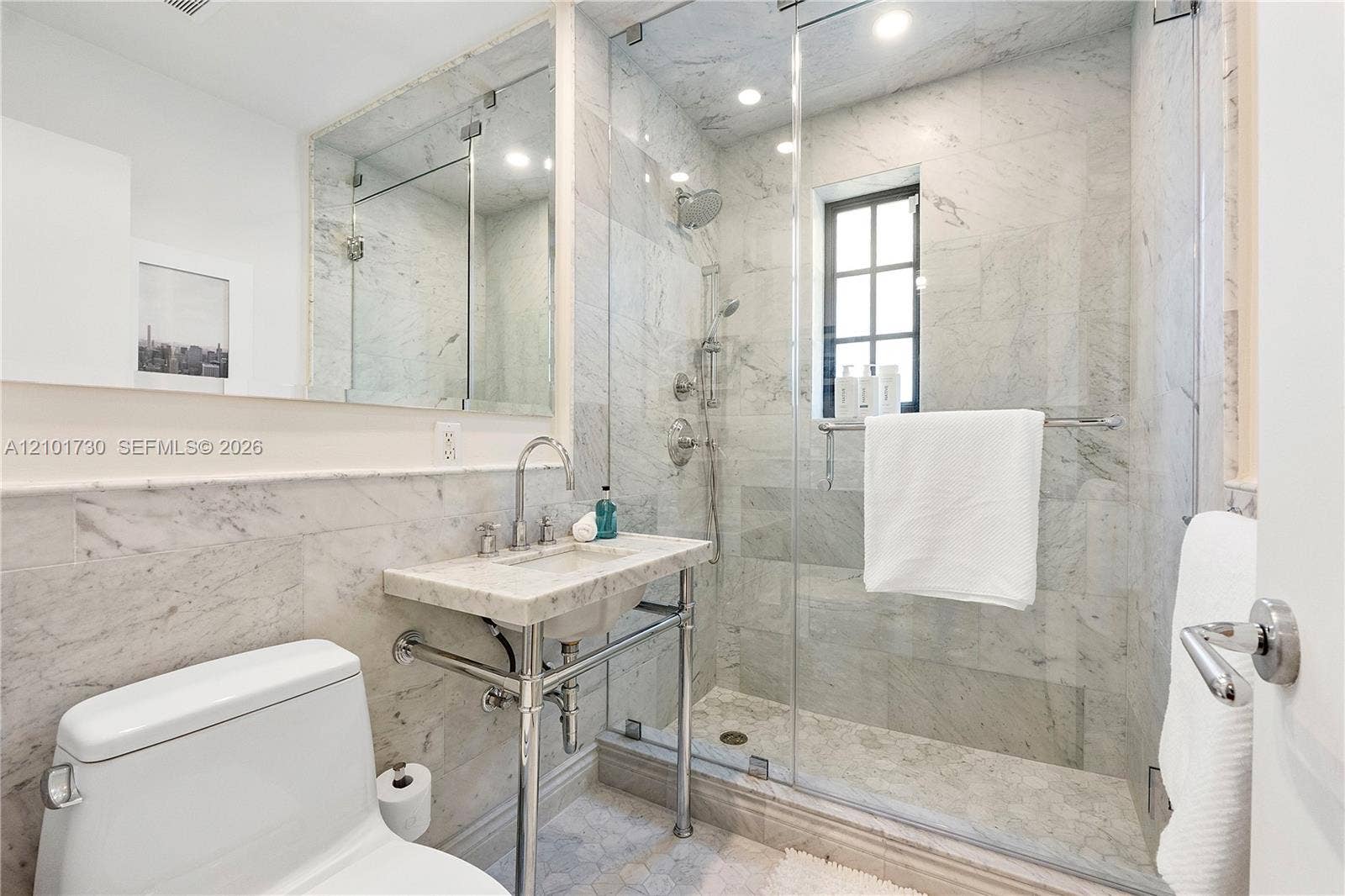435 W 51st Street, Miami Beach, FL 33140 Bathroom featuring stone wall and floor tile, glass-enclosed shower with a handheld fixture, metal console sink, and a wall-to-wall mirror