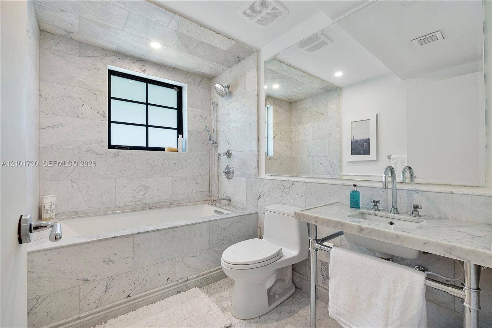 435 W 51st Street, Miami Beach, FL 33140 Bathroom featuring stone tile surround, tub with handheld shower fixture, stone-topped console vanity with integrated basin, polished chrome plumbing fixtures, and wall-to-wall mirror
