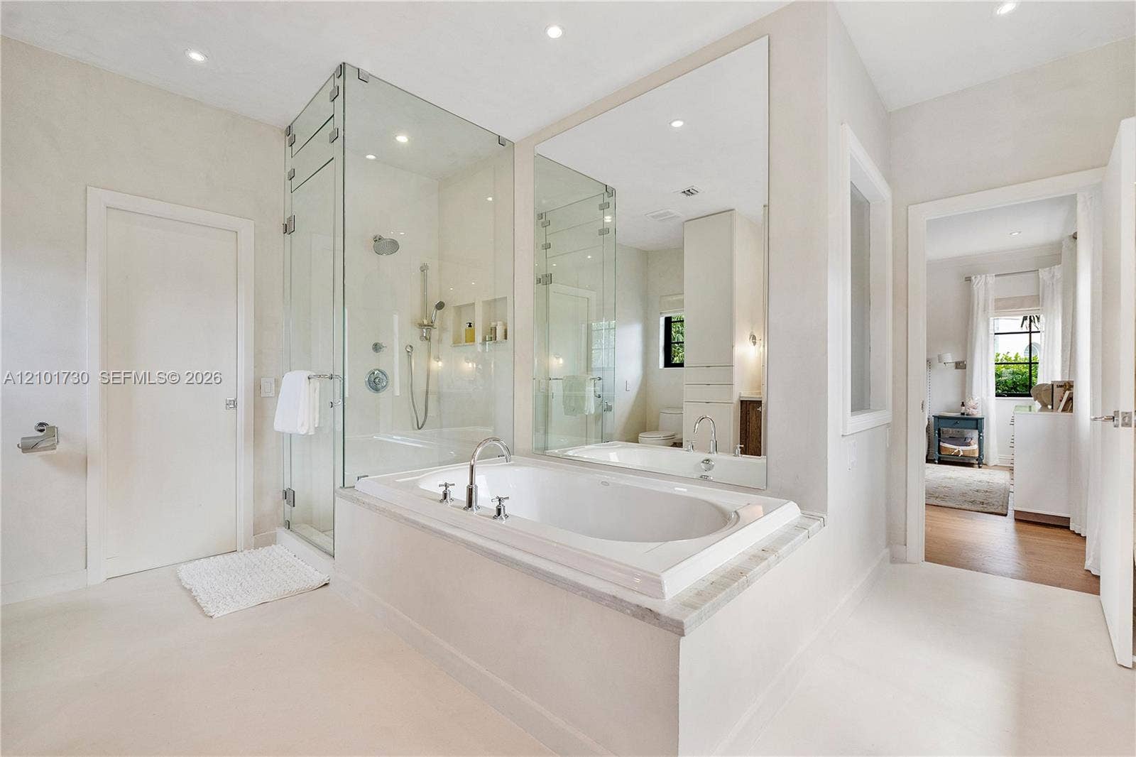 435 W 51st Street, Miami Beach, FL 33140 Soaking tub with a stone-surround deck, glass-enclosed walk-in shower, wall-to-wall mirror, and recessed lighting