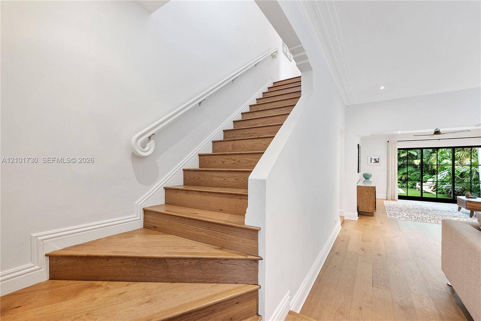 435 W 51st Street, Miami Beach, FL 33140 Staircase featuring wood-finish treads, a white handrail, and white millwork