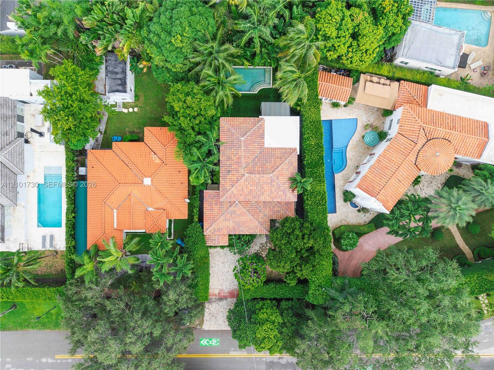 435 W 51st Street, Miami Beach, FL 33140 Aerial perspective featuring a multi-gabled terracotta tile roof, dense perimeter landscaping, and a rectangular in-ground swimming pool