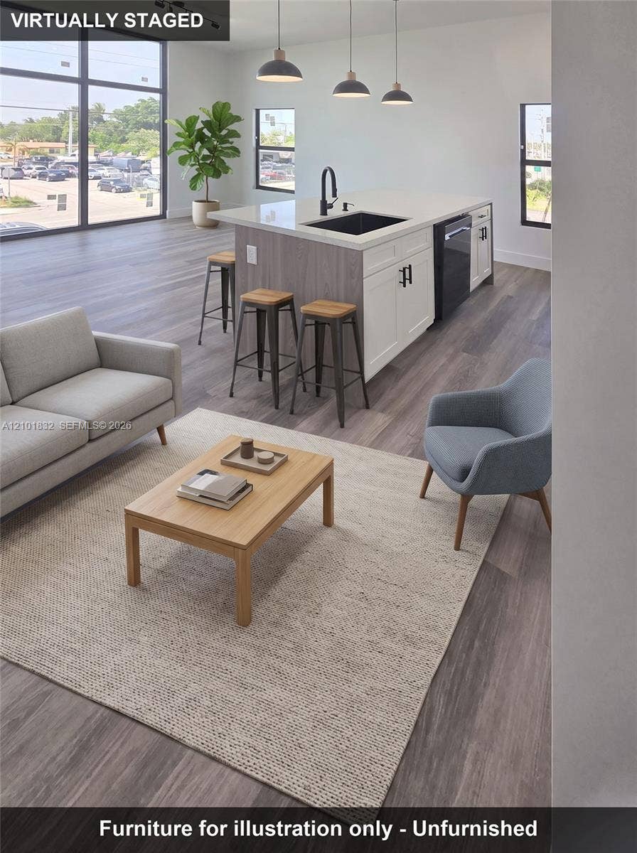 401 Pembroke Road, #201, Hallandale Beach, Hallandale Beach, FL 33009 Kitchen island featuring quartz countertops, two-tone cabinetry, a black undermount sink, and three pendant lights, finished with wood-finish flooring and floor-to-ceiling windows