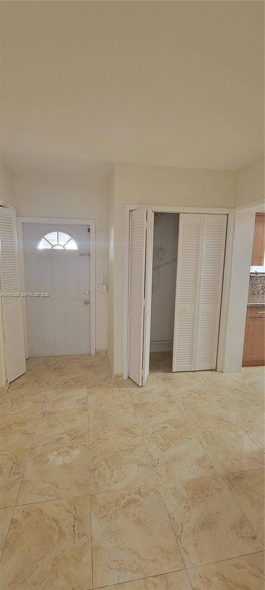 5795 W 13th Court, Hialeah, Hialeah, FL 33012 Entryway featuring light-toned tile flooring, a white paneled door with a semi-circular transom window, and dual white louvered closet doors
