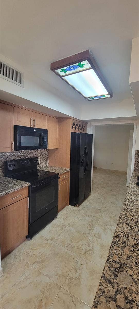 5795 W 13th Court, Hialeah, Hialeah, FL 33012 Kitchen featuring wood cabinetry with built-in wine storage, stone countertops, black appliance suite, and stained glass flush-mount ceiling light