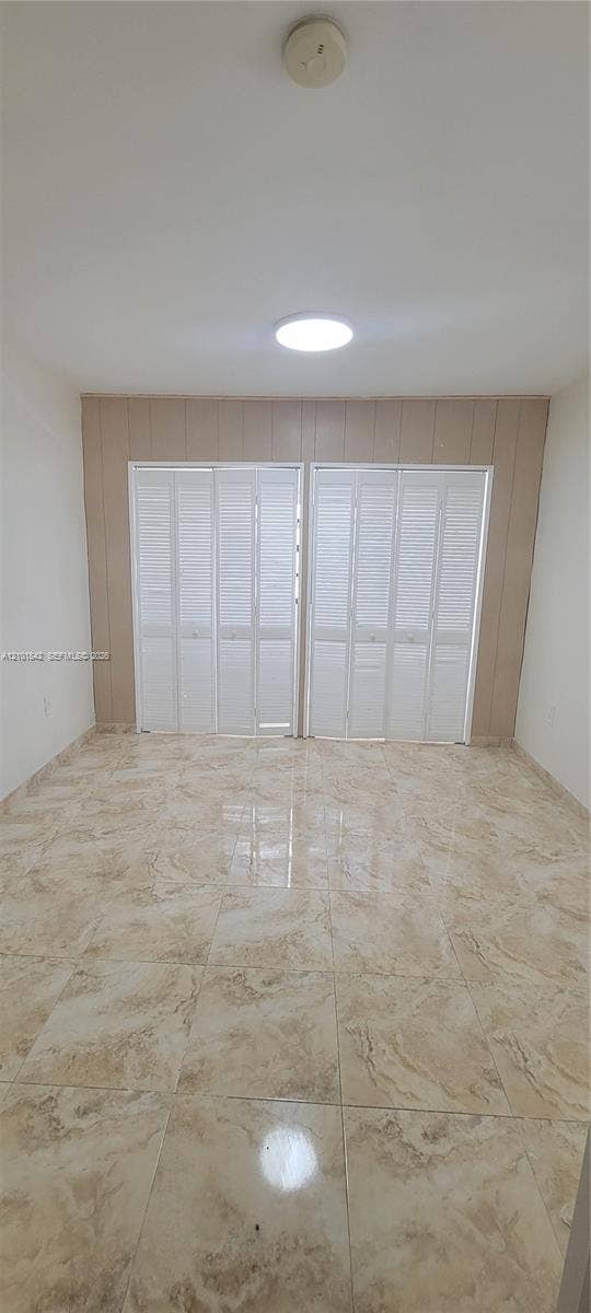 5795 W 13th Court, Hialeah, Hialeah, FL 33012 Large-format tile flooring, dual white louvered bifold closet doors, and recessed ceiling lighting