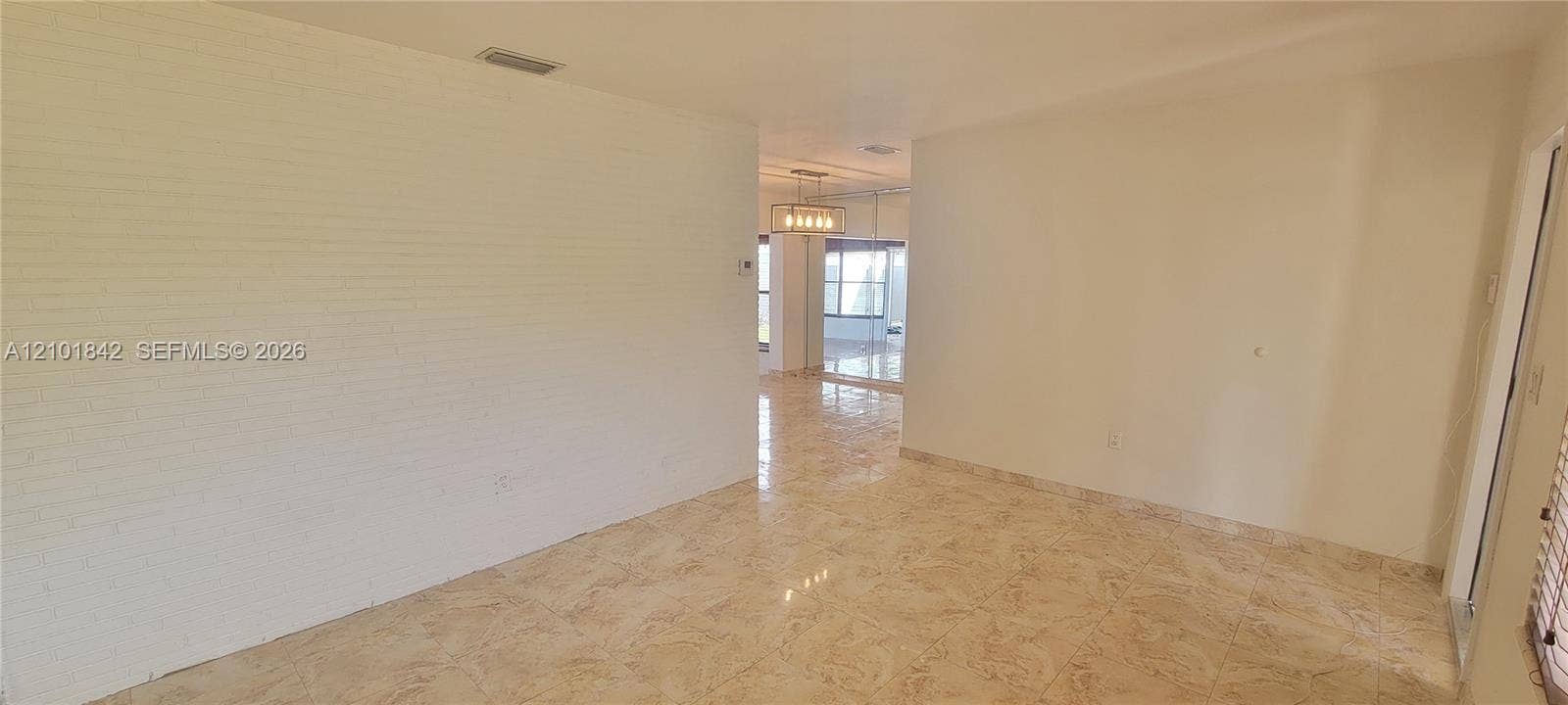 5795 W 13th Court, Hialeah, Hialeah, FL 33012 Interior space featuring white-painted brick walls, polished tile flooring, and a multi-light metal chandelier