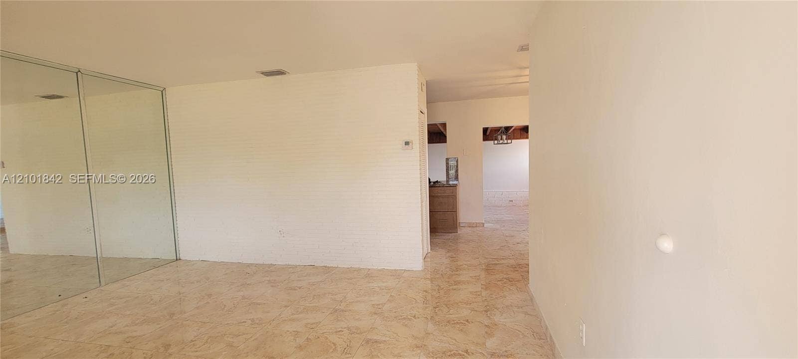 5795 W 13th Court, Hialeah, Hialeah, FL 33012 Interior space featuring large-format polished tile flooring, floor-to-ceiling mirrored wall paneling, and painted brick wall surfacing