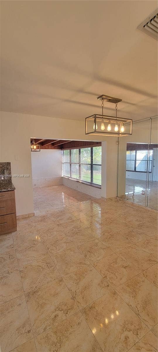 5795 W 13th Court, Hialeah, Hialeah, FL 33012 Polished stone-finish tile flooring, rectangular geometric chandelier with five exposed bulbs, mirrored wall paneling, and large-paned windows featuring exposed wood-beam ceiling detailing