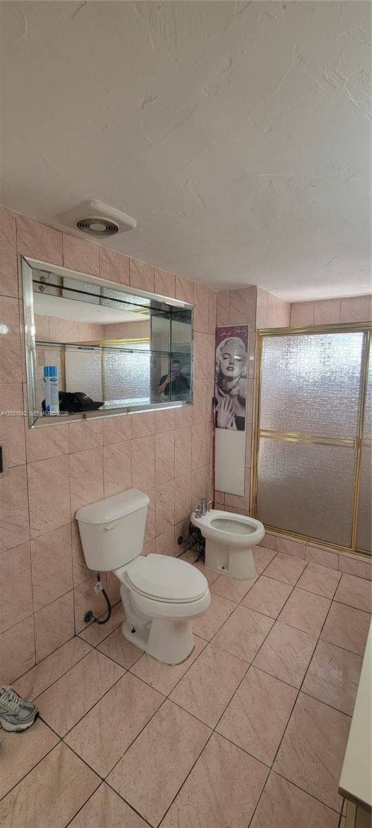 5795 W 13th Court, Hialeah, Hialeah, FL 33012 Bathroom featuring ceramic wall and floor tiling, a bidet, a glass-enclosed shower, and a built-in wall mirror