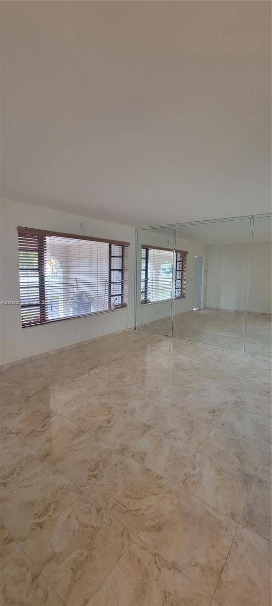 5795 W 13th Court, Hialeah, Hialeah, FL 33012 Polished stone-finish flooring, floor-to-ceiling wall mirrors, and large rectangular windows with wooden blinds