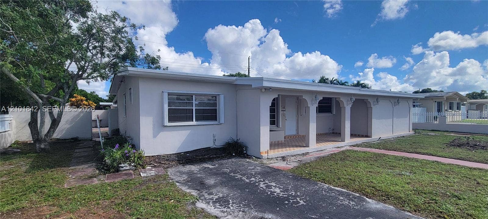5795 W 13th Court, Hialeah, Hialeah, FL 33012 Single-story exterior featuring a covered front porch with arched architectural detailing, light-toned stucco facade, tiled porch flooring, and a paved driveway