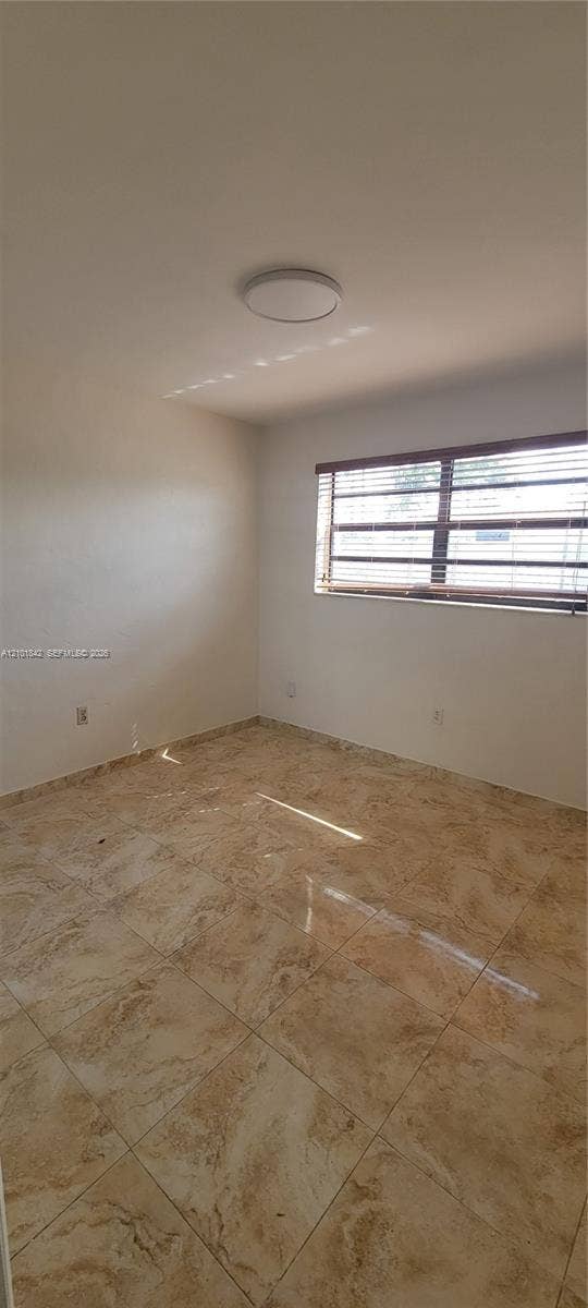 5795 W 13th Court, Hialeah, Hialeah, FL 33012 Neutral-toned ceramic tile flooring, solid-surface wall finishes, ceiling-mounted light fixture, and window with horizontal blinds