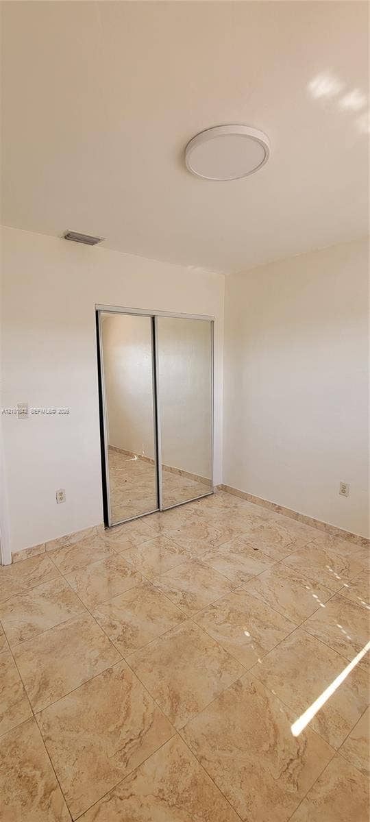 5795 W 13th Court, Hialeah, Hialeah, FL 33012 Neutral-toned tile flooring, flush-mount circular ceiling lighting, and sliding mirror-panel closet doors
