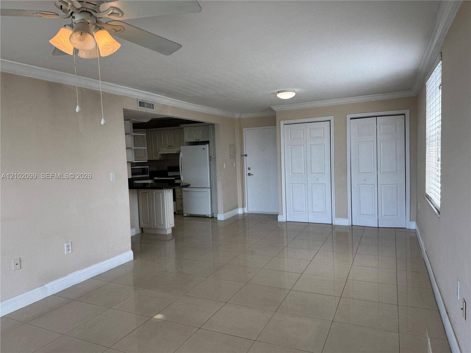13120 SW 92nd Avenue, #B-PH1, Miami, Miami, FL 33176 Living area featuring large-format tile flooring, crown molding, double-panel closet doors, and a ceiling fan with integrated light fixture