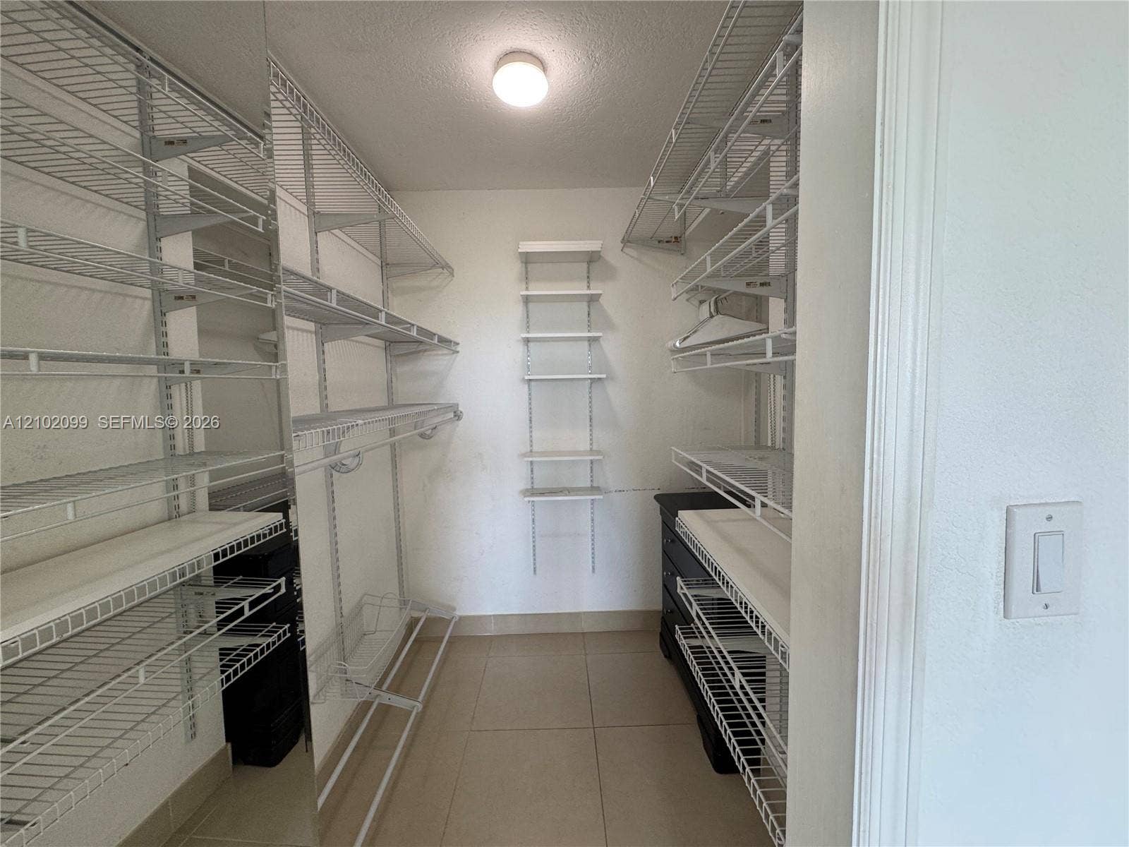 13120 SW 92nd Avenue, #B-PH1, Miami, Miami, FL 33176 Walk-in closet featuring white wire shelving, wall-mounted racks, tile flooring, and a flush-mount light fixture
