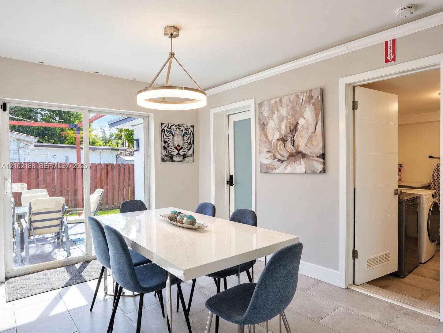 Sliding glass door, contemporary circular chandelier, crown molding, and neutral tile flooring