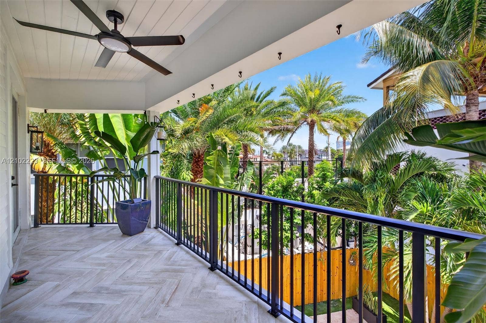 An expansive covered balcony of the primary suite offers a beautiful Tropical escape, surrounded by swaying palms and lush greenery with generous space for outdoor lounging, beautiful tile flooring and a cooling ceiling fan. Its an inviting retreat for morning coffee evening cocktails are simply enjoying the south Florida breeze.