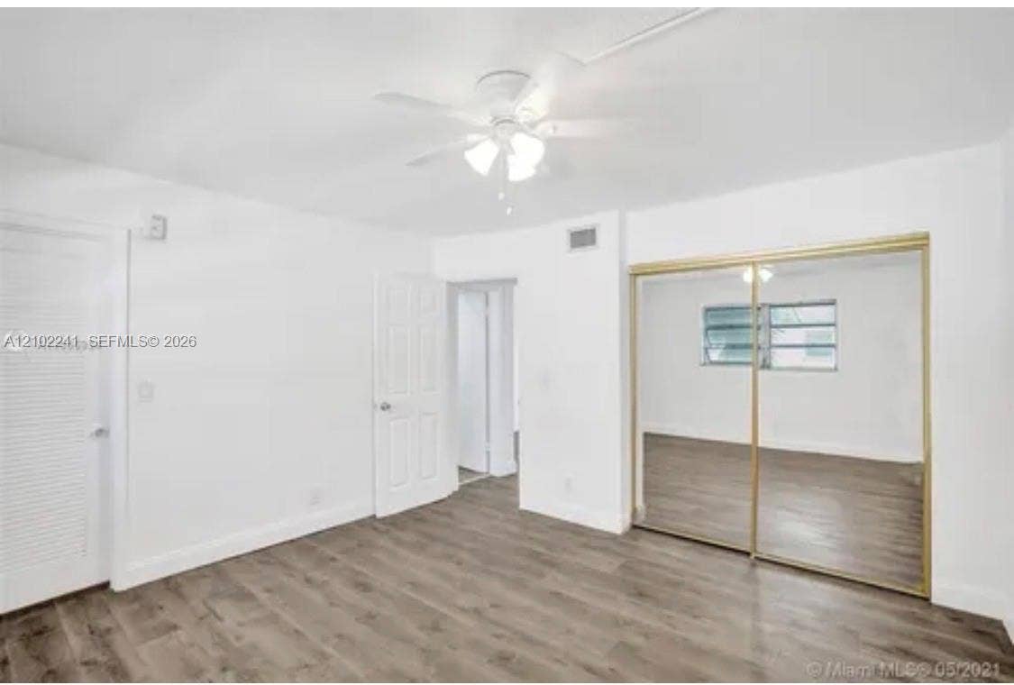Wood-finish flooring, ceiling fan with integrated lighting, and sliding mirrored closet doors