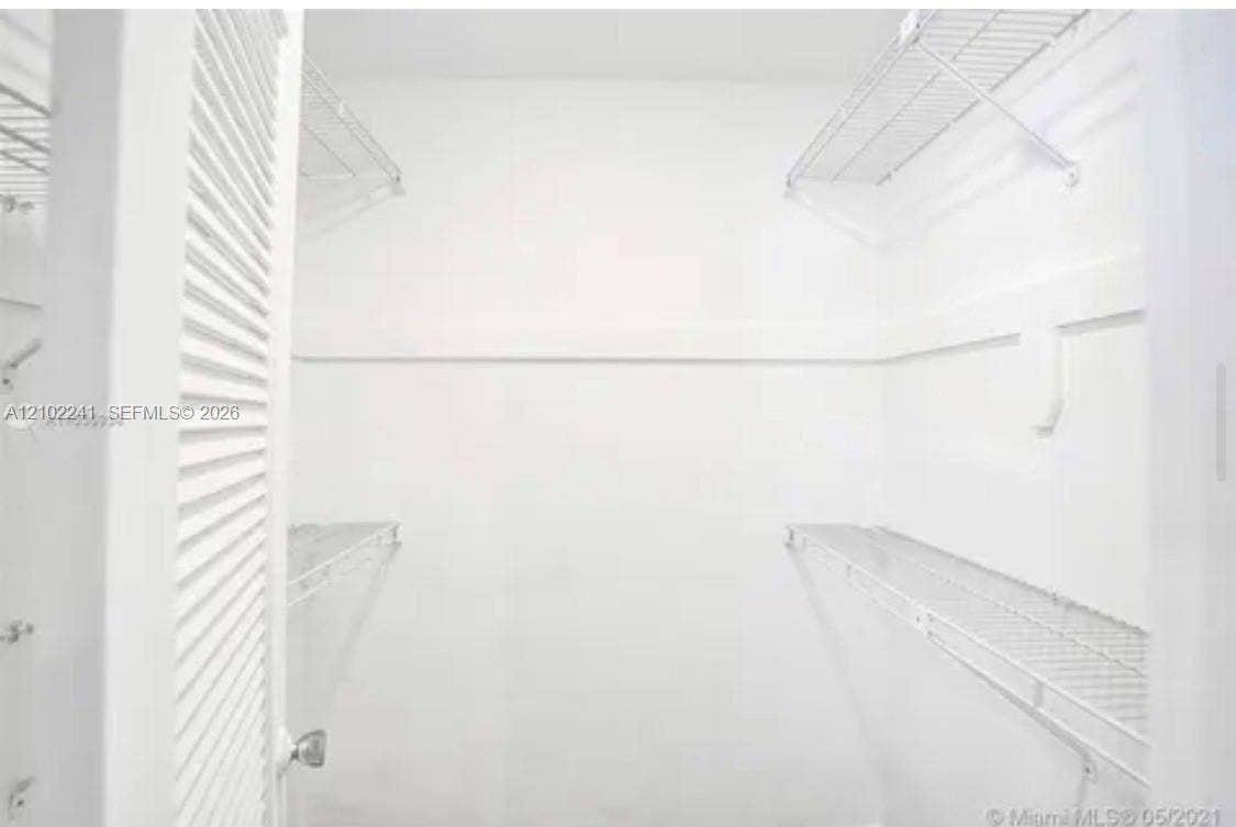 Walk-in closet featuring tiered wire shelving and a louvered door