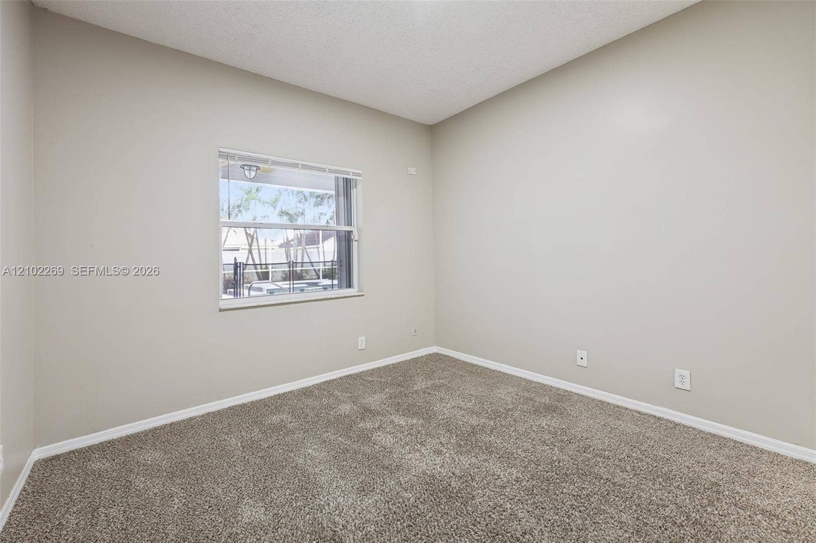 Neutral-toned interior room featuring wall-to-wall carpeting and a single-hung window with integrated blinds