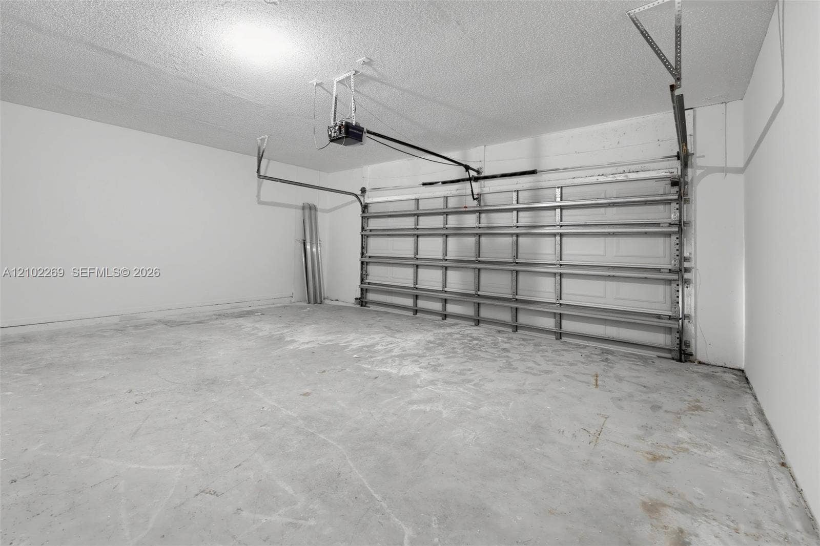 Enclosed garage featuring finished white walls, a concrete floor, and an automated overhead door system
