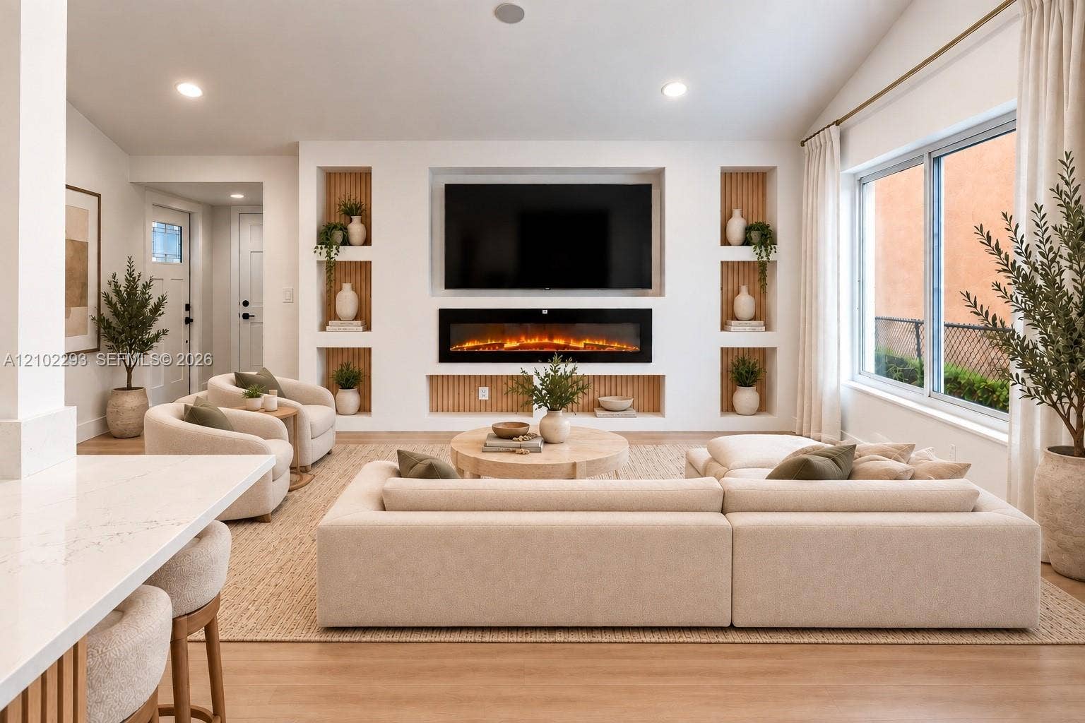 11056 NW 23rd Court, Sunrise, FL 33322 Living area featuring a custom media wall with a built-in electric fireplace, vertical slat wood detailing, recessed shelving, and wood-finish flooring